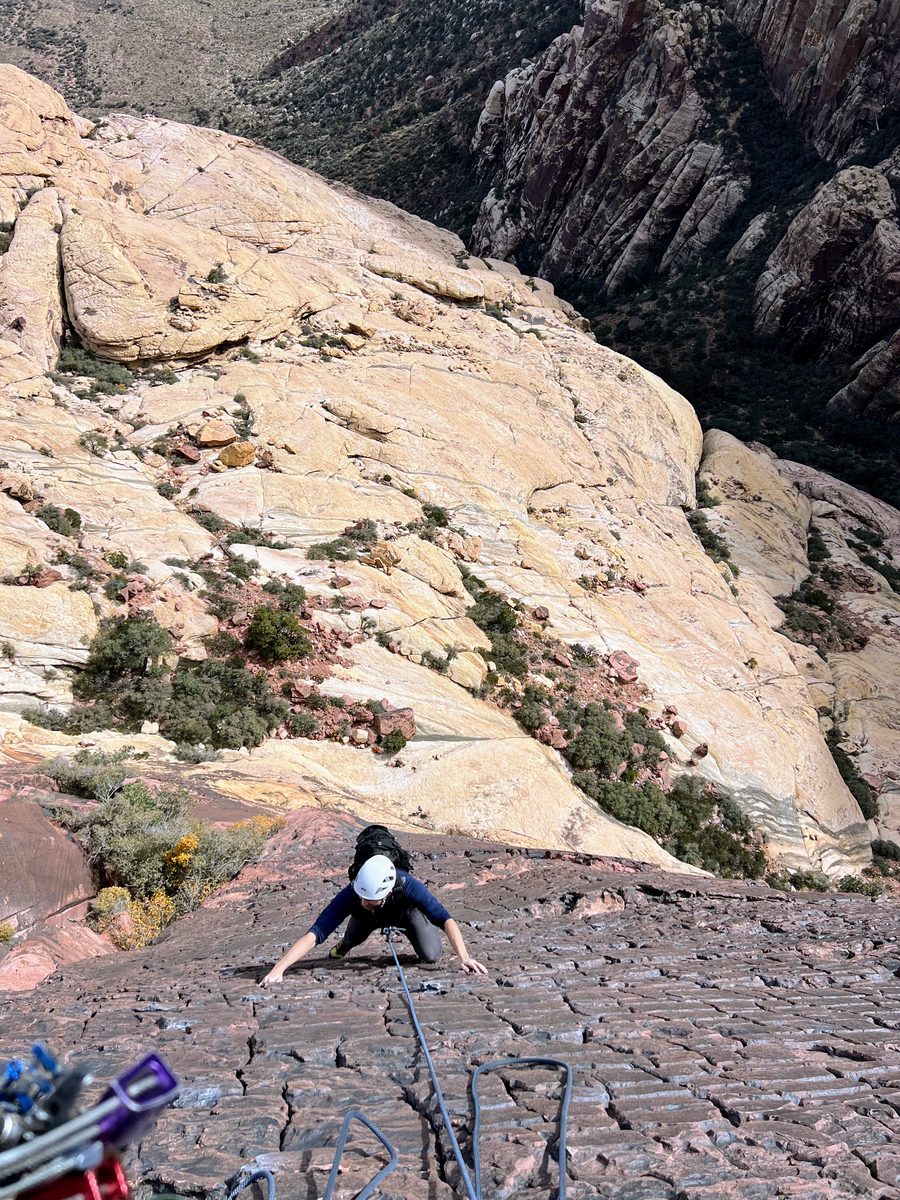 Climber ascending dark sandstone face, Red Rock Canyon, Nevada